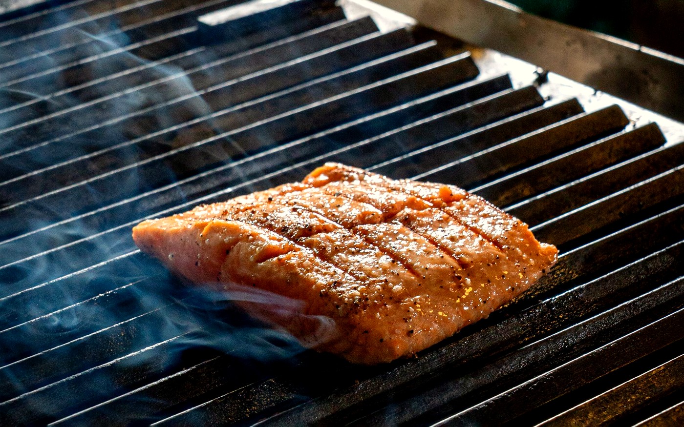 Fish fillet grilling with smoke rising