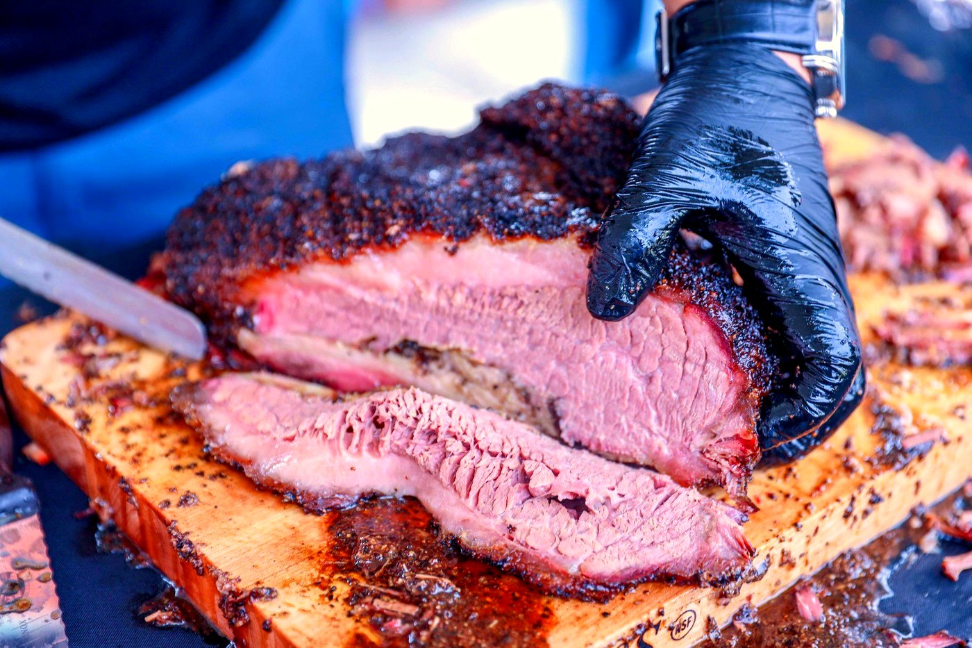 Sliced smoked brisket with a dark bark on a cutting board