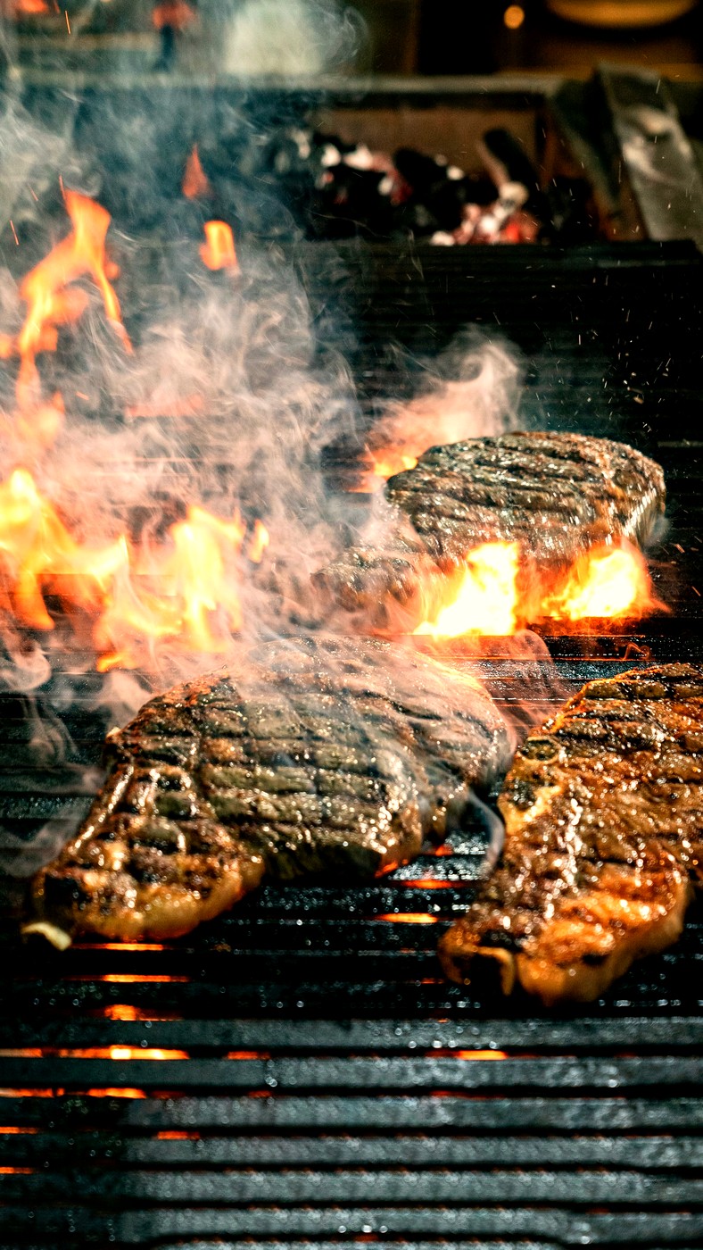 Steaks grilling over open flames