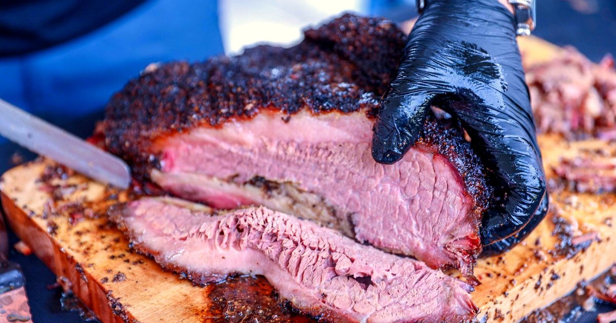Sliced smoked brisket with a dark bark on a cutting board